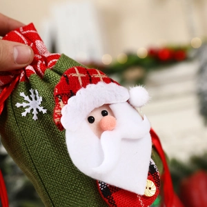 Close-up of green burlap Christmas gift bag featuring a 3D Santa and drawstring design