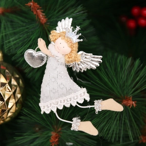 Detail of a white Christmas angel ornament with silver wings on a festive pine tree branch