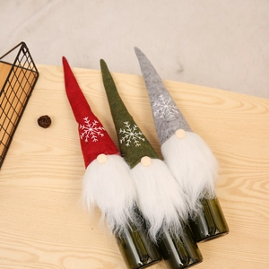 Close-up of three plush Christmas gnome wine bottle covers with snowflake embroidery detail