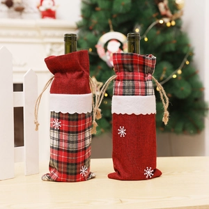 Detail of burlap Christmas wine bottle bags with red plaid and white snowflake patterns