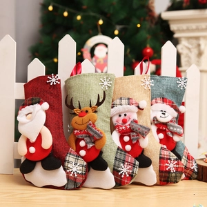 Détail de quatre chaussettes de Noël colorées en lin avec des motifs 3D du Père Noël et renne