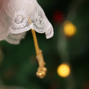 Detail of white lace angel ornament with gold chain against festive bokeh background