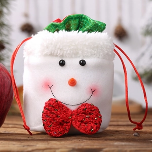 Charming snowman Christmas drawstring burlap gift bag with red bow on warm wood background