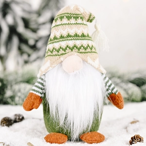 Green knitted Christmas gnome decoration on snowy pine branch background for holiday decor