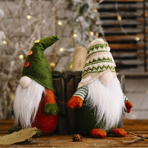 Pair of festive knitted Christmas Gnomes with green hats and white beards on wooden background