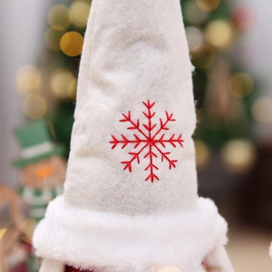 Macro detail of white felt Christmas gnome hat with red embroidered snowflake and plush trim