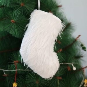 Detail of white faux fur Christmas stocking hanging on a festive green tree branch