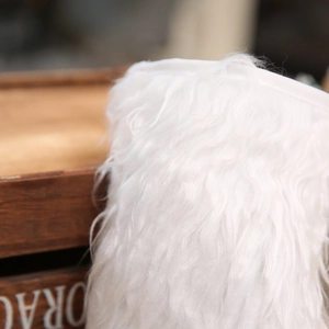 White plush faux fur Christmas stocking hanging on a rustic dark wooden box