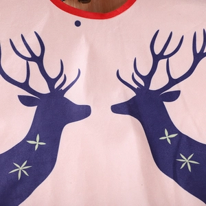 Detail of pink Christmas tree skirt featuring navy reindeer prints and red piping trim