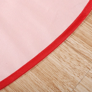 Detail of pink Christmas tree skirt with durable red ribbed ribbon edge on wood background