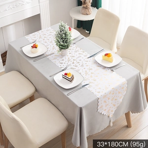 Detail of white Christmas table runner with gold tree patterns and laser-cut edges