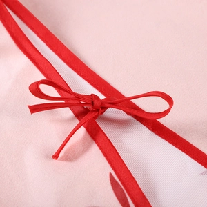 Detailed close-up of pink velvet Christmas tree skirt with elegant red ribbon bow