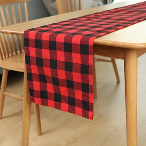 Red and black buffalo plaid table runner made of cotton linen on a rustic wooden dining table