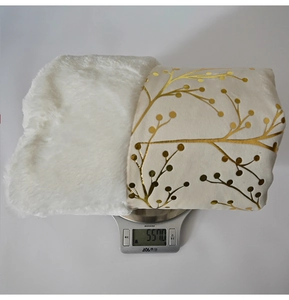 Close-up of plush white Christmas tree skirt with golden branch pattern on a scale
