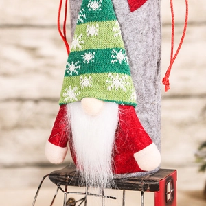 Christmas gnome wine bottle cover with green knit hat and white beard on wood background