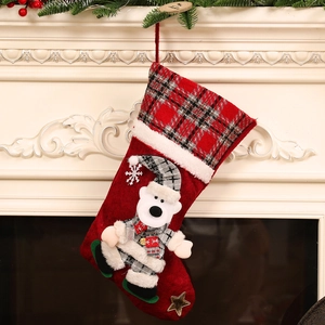 Large red Christmas stocking with cute polar bear doll hanging on a white fireplace
