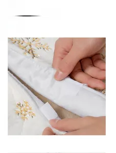 Dettaglio del tappeto per albero di Natale in peluche bianco con fiocchi dorati e velcro