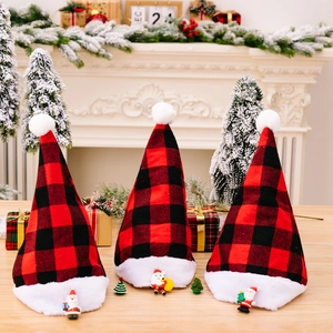 Three red and black buffalo plaid Christmas hats with white plush trim on a festive wooden table