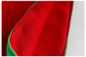 Close-up of red and green velvet elf hat with precise stitching and fabric texture