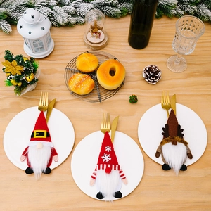 Tres portacubiertos de gnomos navideños en una mesa de madera con decoración festiva