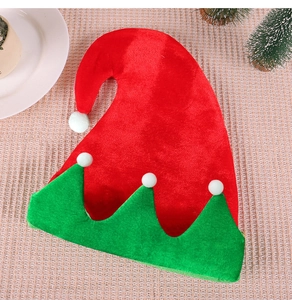Detail of red and green elf hat with plush white balls on a textured festive tablecloth