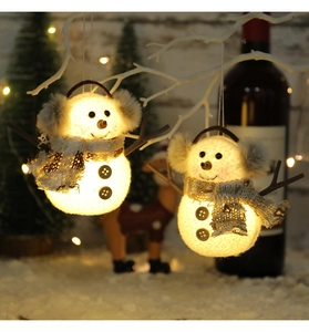 Dettaglio del pupazzo di neve di peluche luminoso con sciarpa a quadri e luce calda