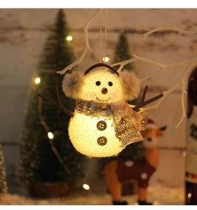 Dettaglio di pupazzo di neve in peluche luminoso con luce calda e sciarpa a quadri
