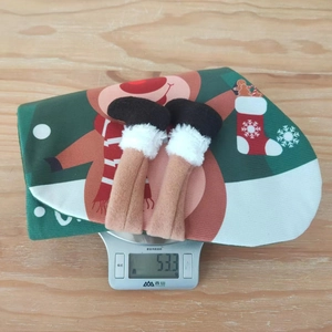Detail view of a green Christmas stocking with reindeer print weighing 53.3g on a scale
