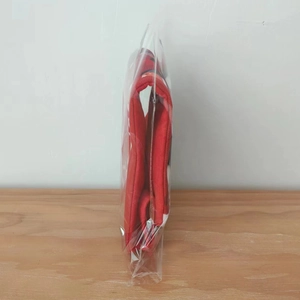 Folded red Christmas stocking in protective transparent packaging on a wooden surface