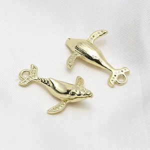 Macro view of gold-plated whale charms with smooth lines and detailed textures for DIY jewelry