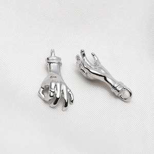 Macro shot of silver metal OK gesture and open hand charms for DIY jewelry making