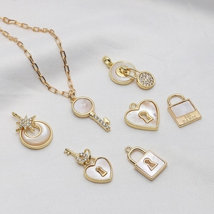 Set di gioielli placcati in oro con ciondoli a cuore in madreperla e chiavi su tessuto