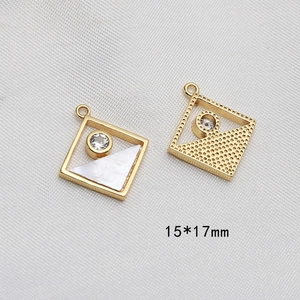 Dettaglio di pendenti geometrici placcati oro con madreperla bianca e pietre di zircone