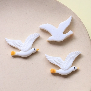 Detail view of cute resin white swan bird charms with yellow beaks for DIY crafts