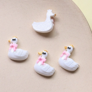 Detail of white swan resin charms with gold crowns and pink bows for DIY hair accessories