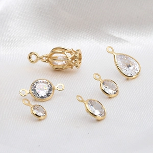 Gouden DIY sieraden hangers met kooi en zirkoon op een elegante witte zijden achtergrond
