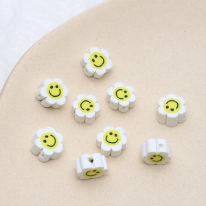 Détail de perles fleurs en argile polymère blanche avec smileys pour bijoux artisanaux