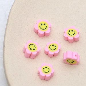 Vue détaillée de perles fleurs en pâte polymère rose avec sourires pour bijoux DIY