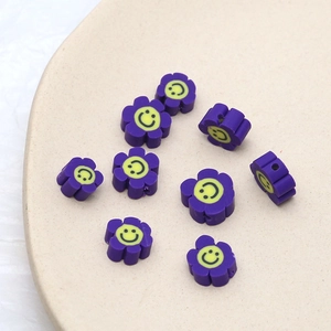 Gros plan de perles fleurs en argile violette avec smiley jaune pour bijoux DIY