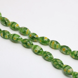 Macro detail of oval green millefiori glass beads with yellow and white floral patterns