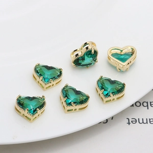 Close-up of six gold-plated heart-shaped charms with deep green zircons for DIY jewelry
