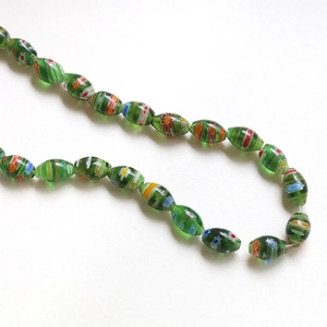 Macro view of green olive-shaped millefiori glass beads with colorful floral patterns