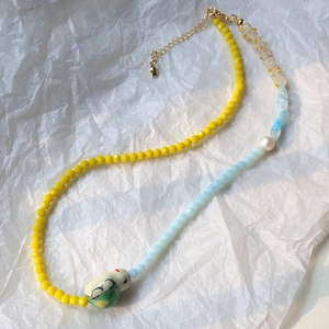 Macro shot of 4mm faceted glass beads and ceramic bird pendant on handmade necklace