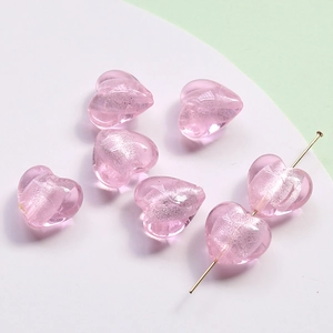 Close-up of pink glass heart beads with silver glitter for DIY jewelry making
