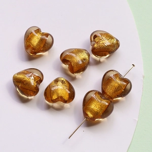 Macro detail of amber heart glass beads with gold foil for DIY jewelry making