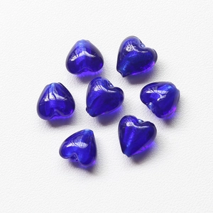 Macro view of seven dark blue heart-shaped glass beads with galaxy glitter for DIY jewelry