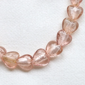 Macro shot of heart-shaped pink glass beads with silver foil interior for DIY jewelry