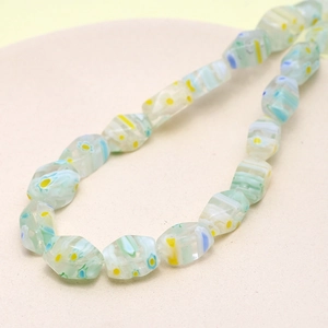 Macro detail of faceted light green glass beads with yellow and blue floral patterns