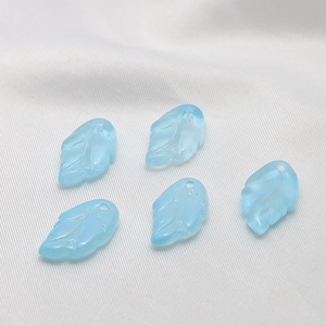 Macro view of light blue translucent glass leaf charms with detailed vein texture