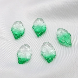 Detailed view of five gradient green glass leaf charms for DIY jewelry making and crafts